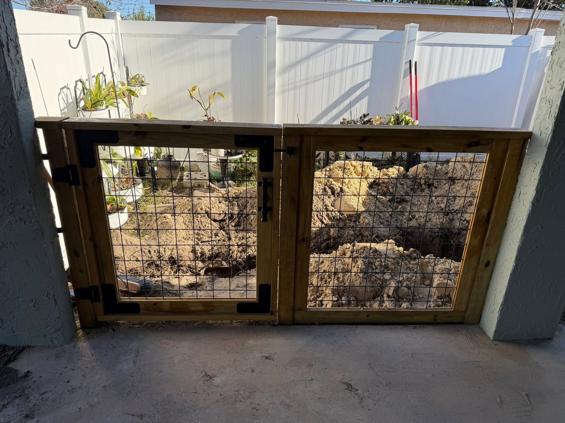 Custom wood-and-wire double gate viewed straight on from the covered patio